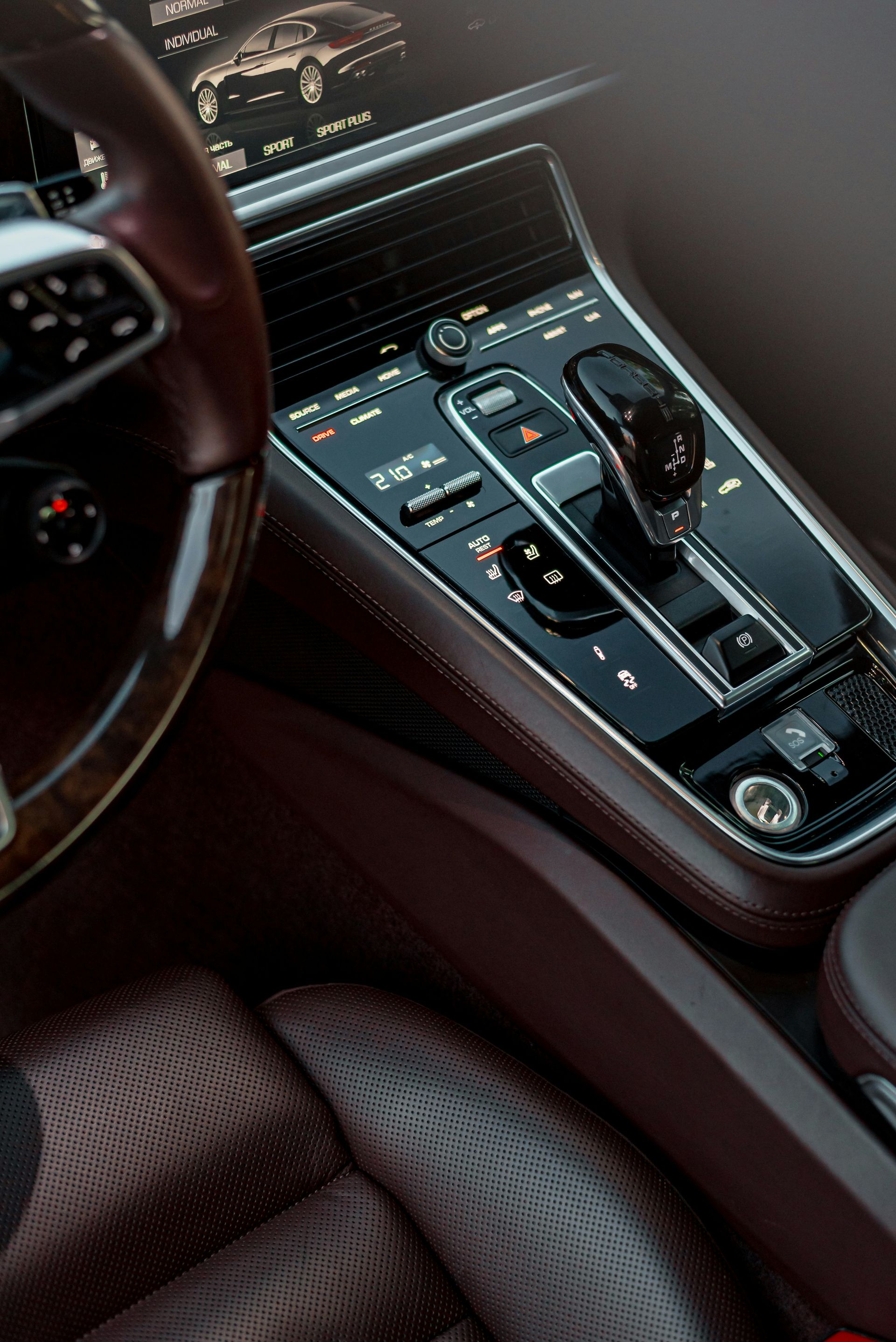 Innenraum eines Luxuswagens mit braunem Lederarmaturenbrett, Lenkrad und Mittelkonsole mit Bedienelementen.