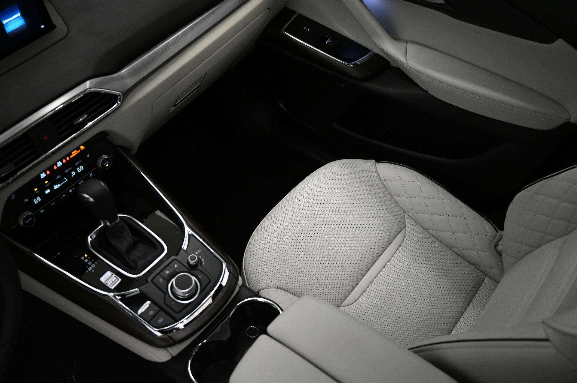 Innenraum des Fahrzeugs mit weißen Ledersitzen, Schalthebel und Infotainment-Display.