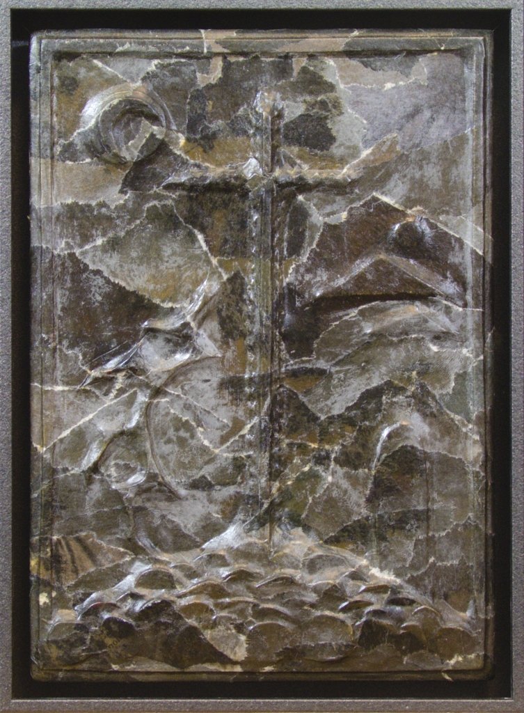 Kleines schwarzes Glanzreliefkreuz, Licht modelliert die Oberfläche von links.