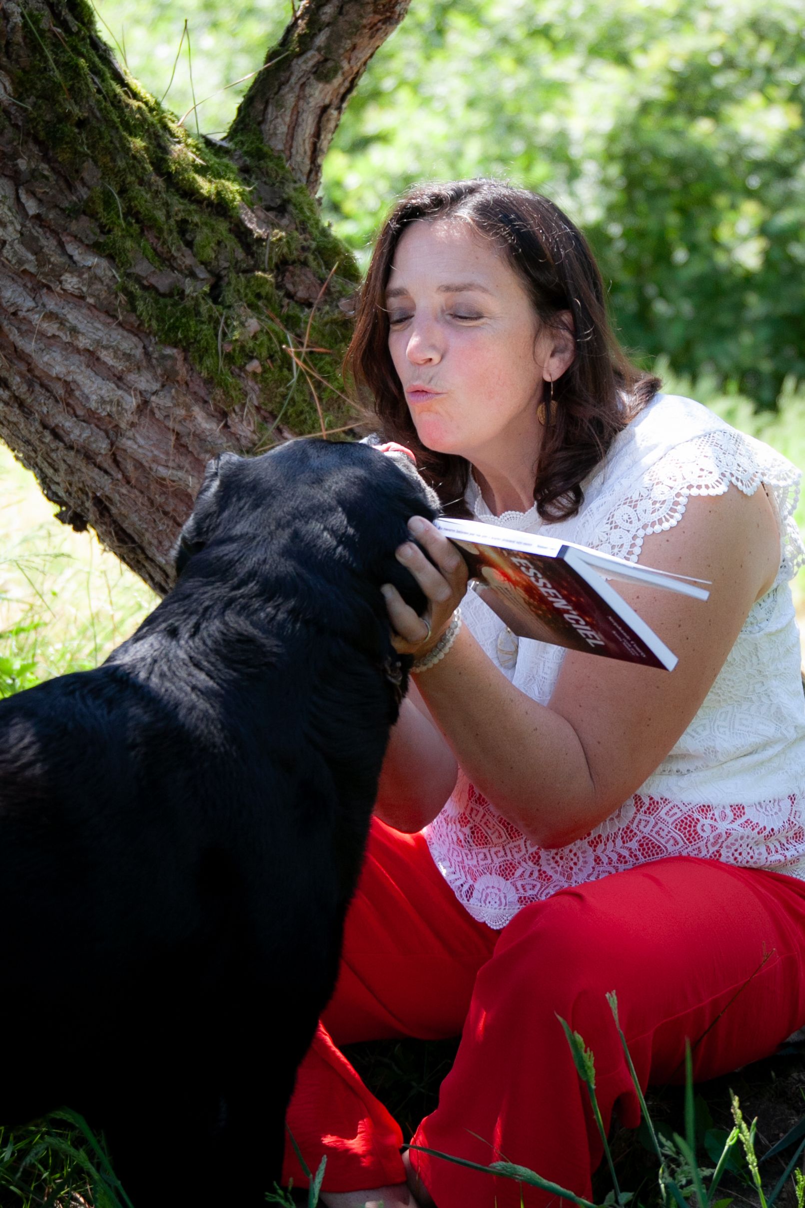 Stéphanie COURTY en nature avec son livre Essen'Ciel et son chien qui vient lui faire un bisous