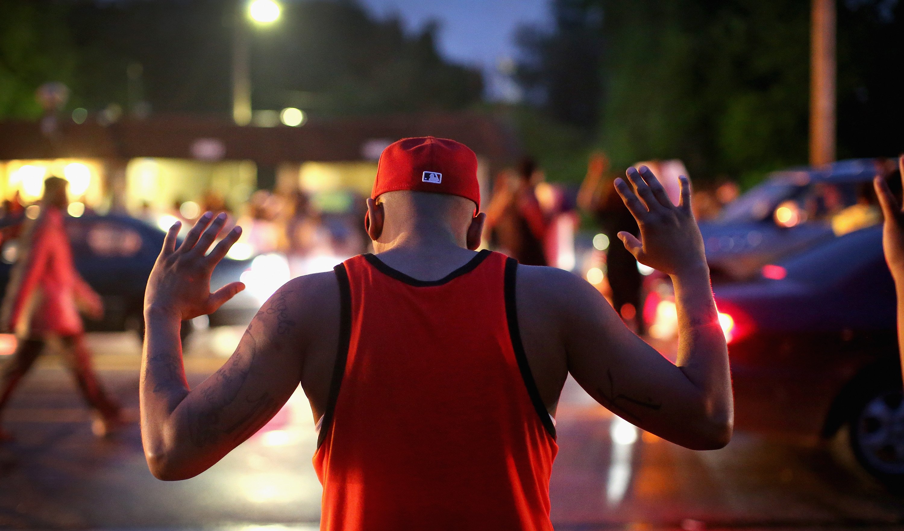 FERGUSON, MO - AUGUST 15: Demonstrators gather along West Florissant Avenue to protest the shooting of Michael Brown on August 15, 2014 in Ferguson, Missouri. Brown was shot and killed by a Ferguson police officer on August 9. Protestors raise their hands and chant