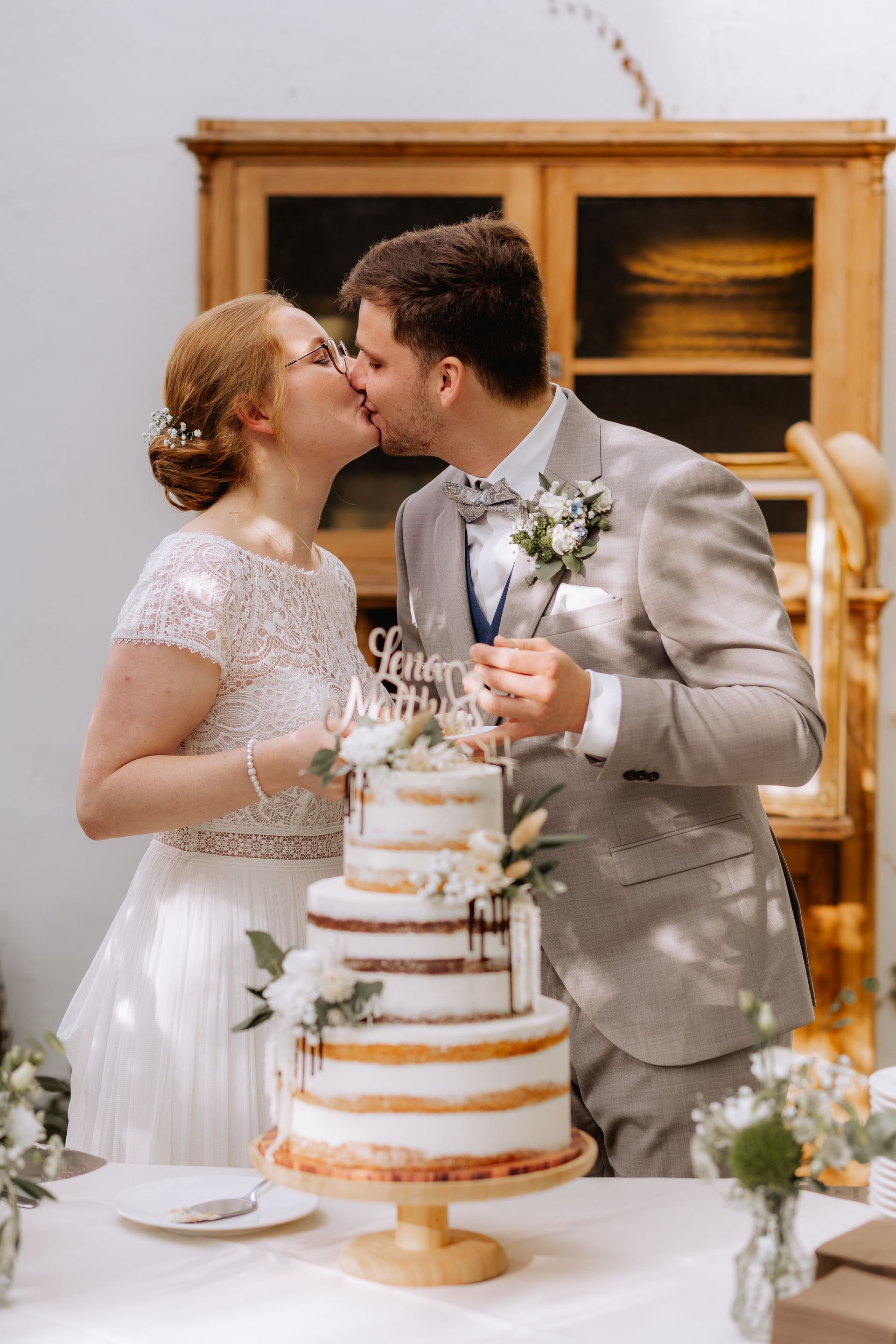 Brautpaarkuss hinter der Hochzeitstorte